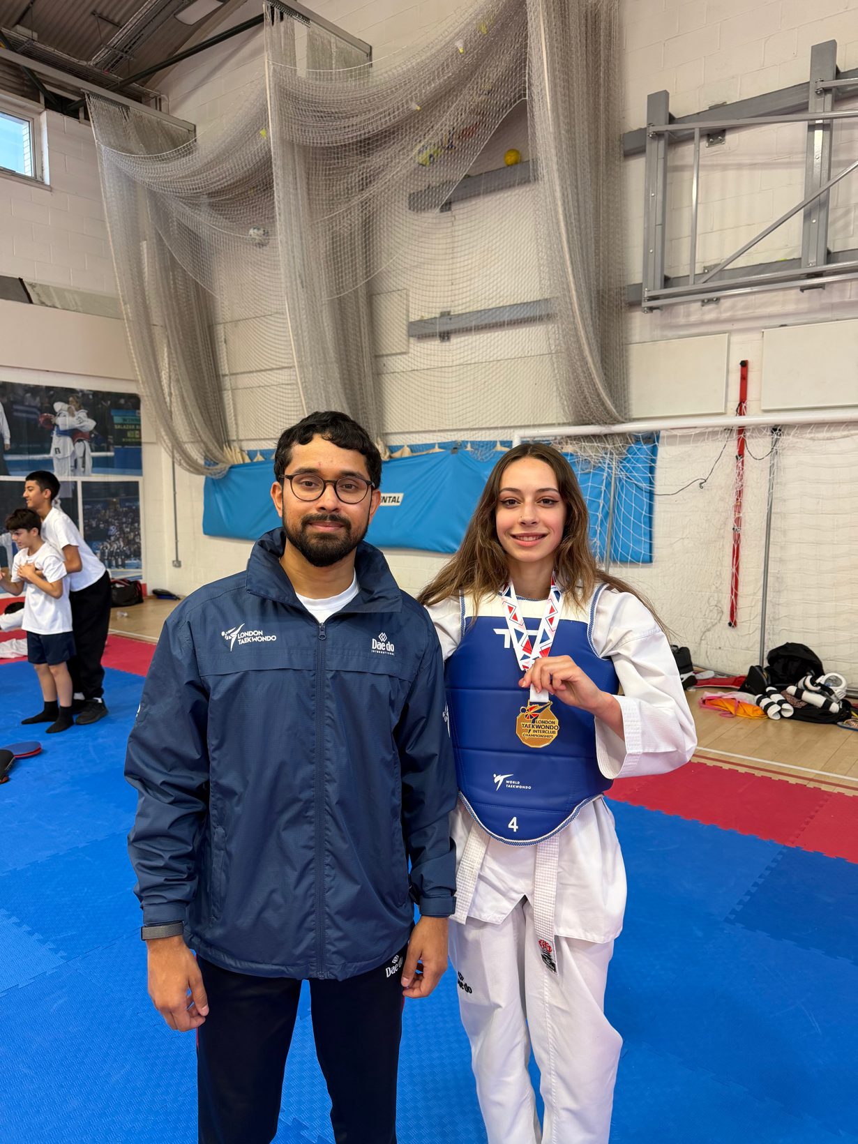 Coach with a Sparks student holding her gold medal at the London Taekwondo Interclub Championships