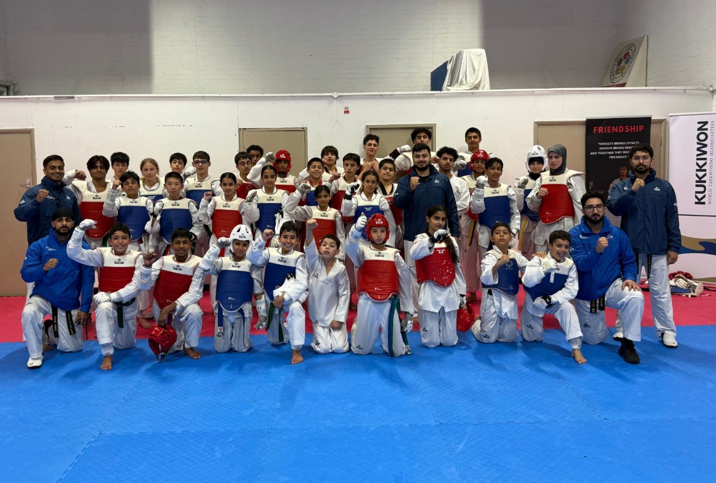 Young students in sparring kit with their coaches