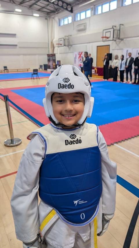 A young Sparks student in sparring kit, smiling
