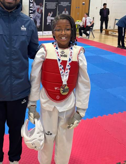 A young Sparks student smiling with her medal